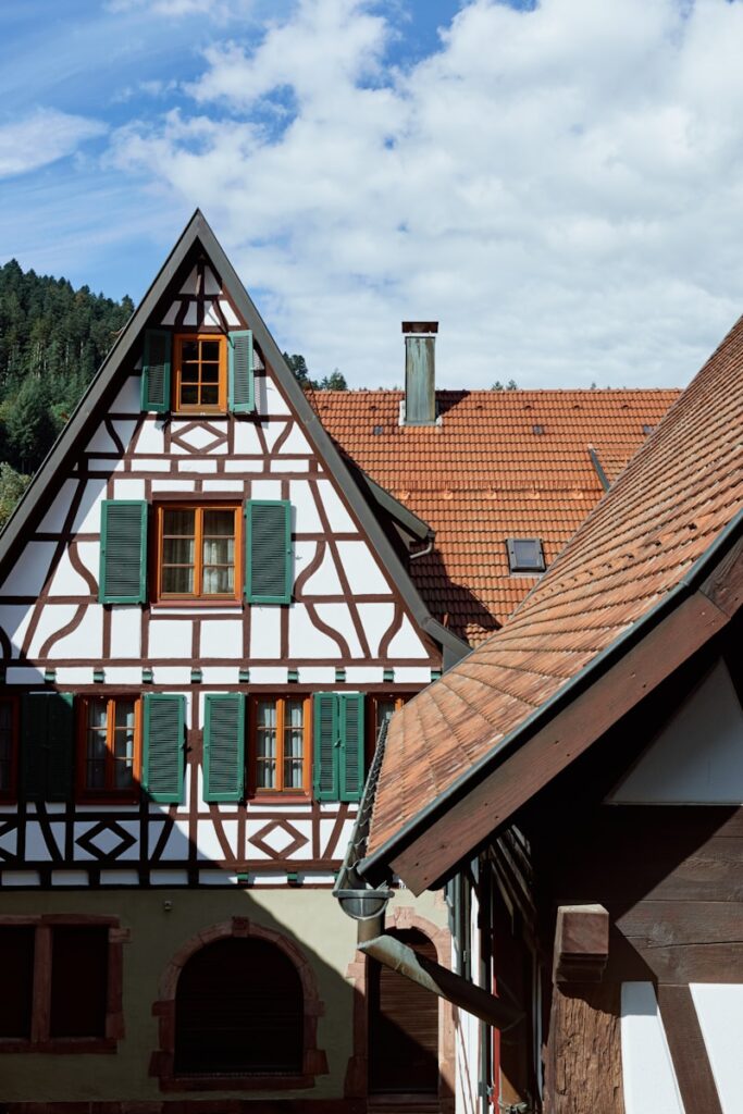 a building with green shutters and a red roof